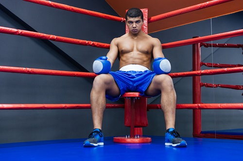 Professional male boxer sitting in the corner of the boxing ring